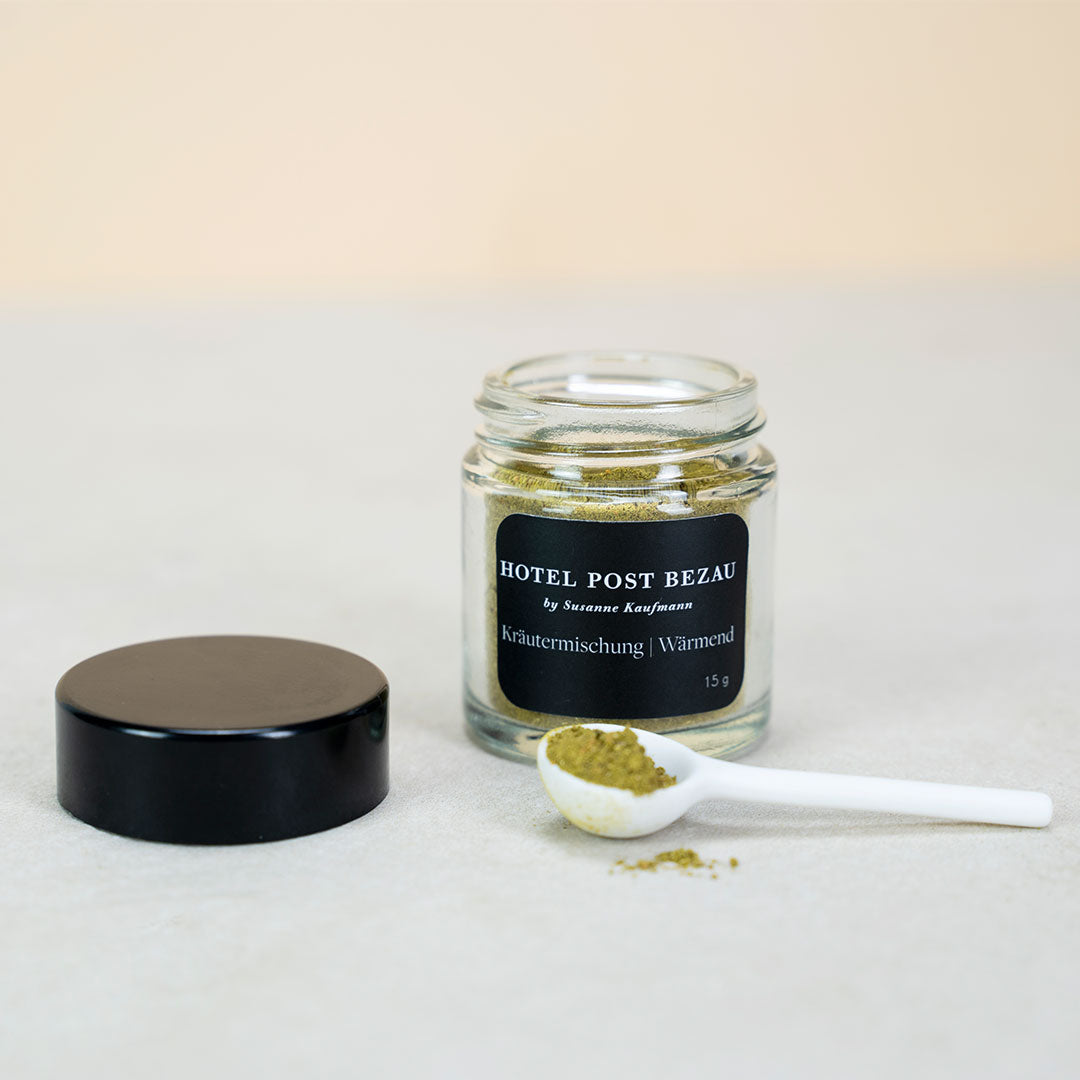Hotel Post Bezau Kräutermischung Wärmend im offenen Glas, daneben der Deckel und ein Löffel mit etwas Kräutermischung
