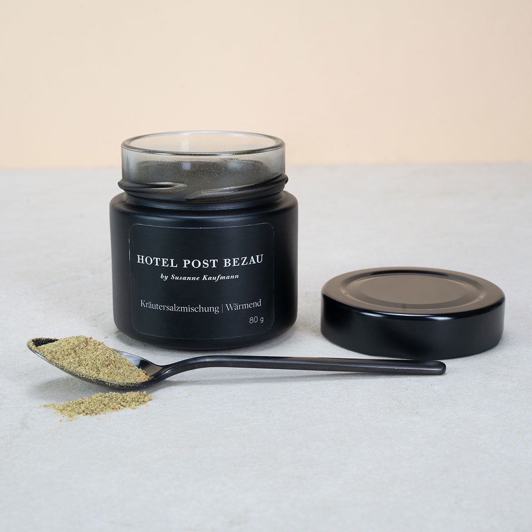 Hotel Post Bezau Kräutersalzmischung Wärmend im offenen Glas, daneben der Deckel und ein Löffel mit etwas Kräutersalzmischung