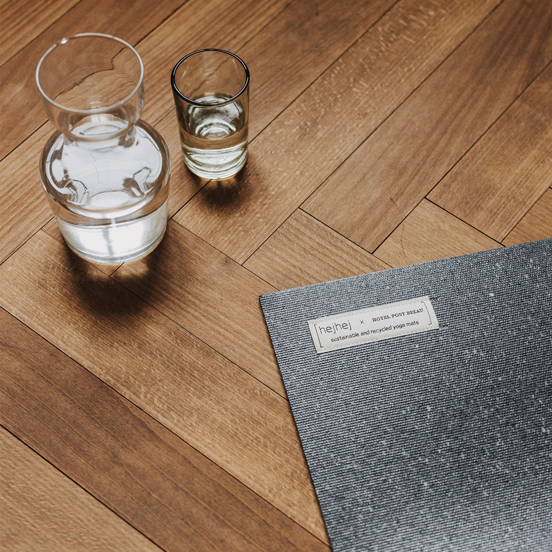 Eher dunkle Yogamatte von hejhej-mats und Hotel Post Bezau, auf Parkettfußboden mit Karaffe und Glas Wasser