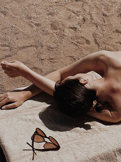 POST BEZAU JUICE Summer Package Frau am Strand auf Handtuch mit Sonnenbrille