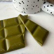 Lade das Bild in den Galerie-Viewer, Organic Matcha Chocolate by Health Bar gebrochen vor Tasse
